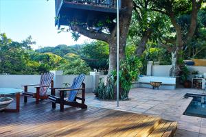 a patio with two chairs and a table and a tree at Marks Cottages in Durban