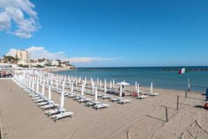 een rij stoelen en parasols op een strand bij La Maison à la Plage - Vista mare & 5min Spiaggia in Santa Marinella