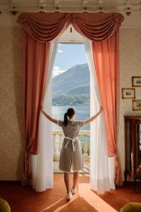 Eine Frau steht vor einem Fenster in der Unterkunft Grand Hotel Villa Serbelloni - A Legendary Hotel in Bellagio