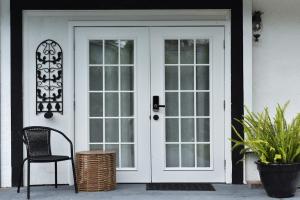a white front door with a chair and a basket at Bedroom and bathroom - perfect for solo traveler in Wellington