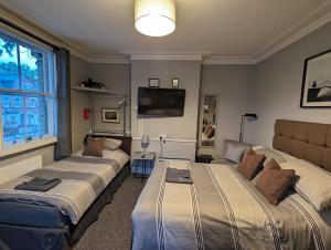 雷丁的住宿－Caversham Lodge，客房设有三张床和一台平面电视。