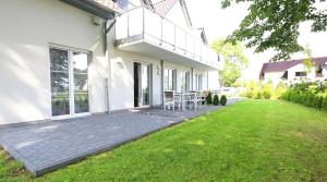 ein weißes Haus mit einer Terrasse und einer Liegewiese in der Unterkunft Haus Sonne - FeWo 01 Sandperle in Thiessow