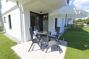a patio with a table and chairs and an umbrella at Villa Strandläufer Whg. 23 MeerMomente mit Terrasse in Baabe