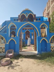 a blue building with a woman standing in the doorway at A R A B I A Golden Palace in Luxor