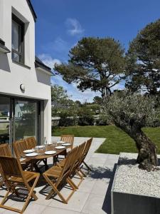 eine Terrasse mit einem Tisch, Stühlen und einem Baum in der Unterkunft Maison au calme, proche plage, wifi in Quiberon