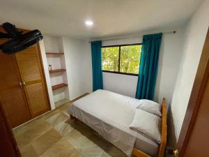 a bedroom with a bed with blue curtains and a window at Casa Boutique Rincon in San Onofre