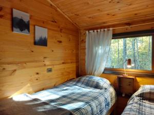 sypialnia z 2 łóżkami w drewnianym domku w obiekcie Estación Benedicto w mieście Manzanar