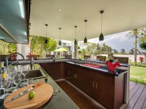an outdoor kitchen with a counter with wine glasses at Villa Luwih in Canggu