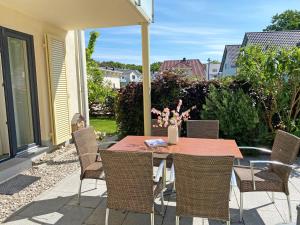 ein Tisch mit Stühlen und einer Vase mit Blumen auf einer Terrasse in der Unterkunft F Haus Sterntaucher Whg 01 mit Terrasse in Thiessow