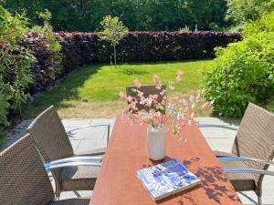 ein Holztisch mit einer Vase mit Blumen darauf in der Unterkunft F Haus Sterntaucher Whg 01 mit Terrasse in Thiessow + 16 Fotos