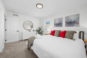 - une chambre blanche avec un grand lit et des oreillers rouges dans l'établissement 6224 S Datura St, à Littleton