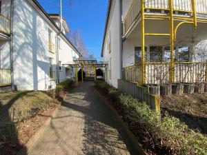 uma passagem ao lado de um edifício branco com toques amarelos em Villa Stoertebeker - Ferienwohnung 17 em Baabe
