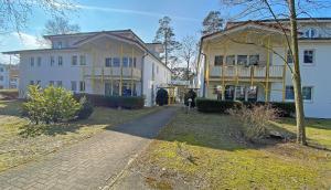 a large white building next to a house at Villa Stoertebeker - Ferienwohnung 17 in Baabe