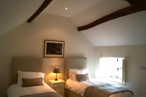 two beds in a room with a window at Two Rose Walk Cottage Cotswolds in Moreton in Marsh