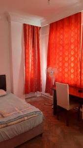 1 dormitorio con cama, escritorio y cortinas rojas en Şirinevler Guest house, en Estambul