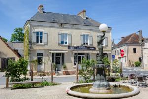 a fountain in the middle of a street with a building at Aux Couleurs de Neuvy in Neuvy-Saint-Sépulchre