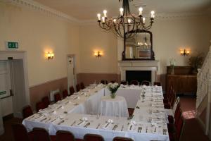 um quarto grande com uma mesa longa com mesas e cadeiras brancas em The White Hart Hotel em Welwyn