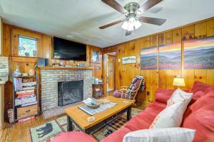 a living room with a red couch and a fireplace at Pet-Friendly Maggie Valley Cabin with Pool Access! in Maggie Valley