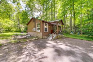 a small cabin in the woods with a picnic table at Pet-Friendly Maggie Valley Cabin with Pool Access! in Maggie Valley