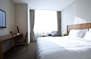 a hotel room with a large bed and a desk at LOTTE City Hotel Myeongdong in Seoul