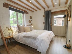 ein Schlafzimmer mit einem großen weißen Bett und einem Fenster in der Unterkunft Holly Cottage - Fold Yards in Belper