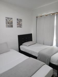 3 Betten in einem Zimmer mit weißen Wänden in der Unterkunft House Hotel Sweet Home 2 apartments in Medellín