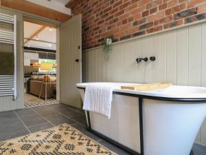 ein Badezimmer mit einer Badewanne und einer Ziegelwand in der Unterkunft Holly Cottage - Fold Yards in Belper + 13 Fotos