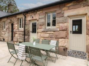 a table and chairs in front of a stone cottage at Hazel Cottage - Fold Yards in Belper