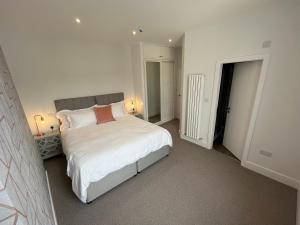 um quarto com uma cama grande e lençóis brancos em Carrick Rooms em Port Saint Mary