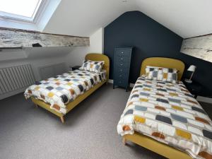 2 camas individuales en un dormitorio con paredes azules en Carrick Rooms, en Port Saint Mary