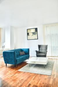 a living room with a blue couch and two chairs at 2 Bedroom Discovery Dock in London
