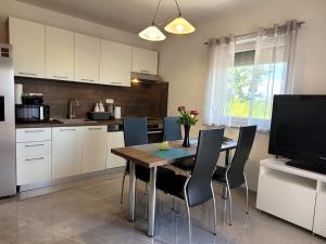 a kitchen with a table with chairs and a television at Apartmani Dani in Sveti Anton