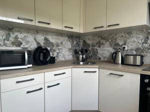 a kitchen with white cabinets and a microwave at Lilli Flensburg Fewo in Flensburg