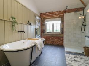 ein großes Badezimmer mit Badewanne und Dusche in der Unterkunft Rowan Cottage - Fold Yards in Belper + 23 Fotos