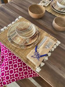 une table en bois avec des assiettes, des fourchettes et des serviettes dans l'établissement Bel appartement au centre gueliz, à Marrakech