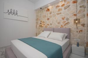 a bedroom with a bed with a stone wall at LUZ BLANCA in Agios Leon