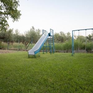 einen Spielplatz mit Rutsche im Gras in der Unterkunft Neromilos Harmony - Roussis Residence in Nerómilos