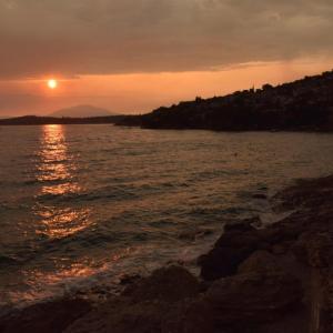 una puesta de sol sobre un cuerpo de agua con la puesta de sol en Salamis Beachfront House, en Salamina