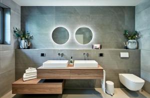 a bathroom with a sink and a toilet and two mirrors at Racers Lodge Grand Prix - mit Hebebühne und Doppelgarage in Bermel +10 photos
