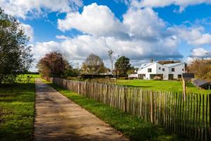 a fence next to a field and a white house at dimensions M in Mont-Saint-Guibert