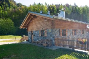 una cabaña de madera con una valla delante en Chalet Cirmolo - Chalet Maso Vecchio immerso nell'Altopiano del Tesino, Trentino, en Castello Tesino