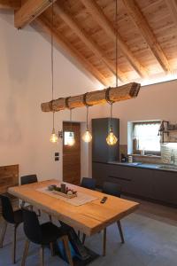 Un comedor con mesa de madera y luces. en Chalet Cirmolo - Chalet Maso Vecchio immerso nell'Altopiano del Tesino, Trentino, en Castello Tesino
