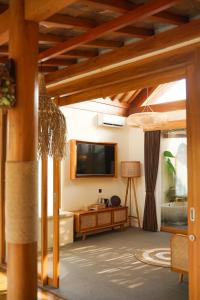 a living room with a flat screen tv and wooden ceilings at LAVILLAS JOGJA in Cebongan