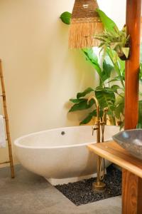 baño con bañera blanca y planta en LAVILLAS JOGJA en Cebongan