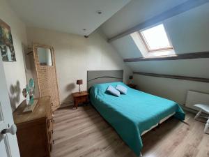 a bedroom with a blue bed and a window at La Coraline in Laubressel