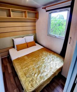 ein kleines Bett in einem kleinen Zimmer mit Fenster in der Unterkunft A deux pas du lac in Ardres