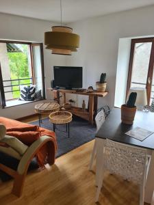 a living room with a table and a tv at Pied des Milles Etang - Les Capucins in Faucogney-et-la-Mer