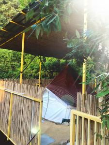 uma tenda atrás de uma cerca de madeira com uma cerca de estacas de madeira, um estofado de estesteres em Bell Glamping - Luxury Bath in Mukteshwar's Nature em Mukteshwar