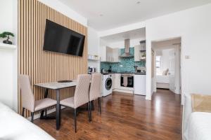 倫敦的住宿－Cosy Apartment in Queens Park，厨房以及带桌椅的起居室。