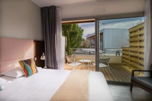 um quarto de hotel com uma cama e uma varanda em Hype Hôtel em Biscarrosse
